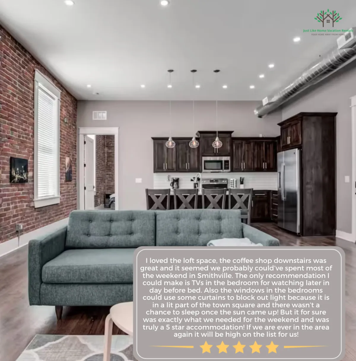 A cozy living area is shown with a comfortable sofa, an adjacent kitchen area, and an exposed brick wall. Stylish lighting fixtures cast a warm glow, and natural light filters through, accentuating the high ceilings and contemporary yet inviting atmosphere.