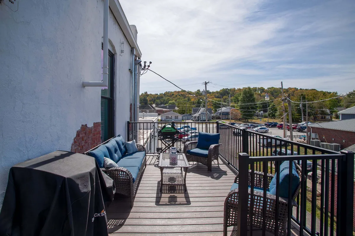 The scene features a comfortable outdoor seating arrangement, a grill, and a decorative table, ideal for hosting meals or casual get-togethers. The mood is casual and social, with sunset lighting that evokes the idea of dining or relaxing outdoors well into the evening.